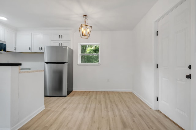 3204 N Ridge Rd, Tallahassee, FL 32305 - kitchen with appliances with stainless steel finishes, light wood-style flooring, white cabinets, hanging light fixtures, and a chandelier