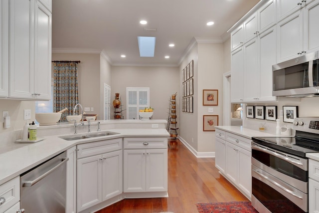 kitchen featuring sink, a skylight, white cabinets, and appliances with stainless steel finishes