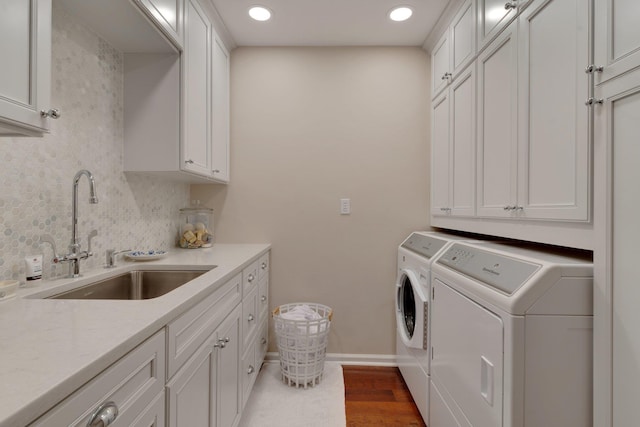 laundry room featuring cabinets, dark hardwood / wood-style floors, washer and clothes dryer, and sink