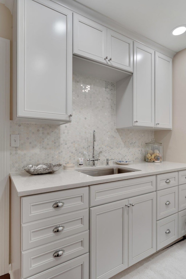 kitchen with white cabinetry, backsplash, and sink