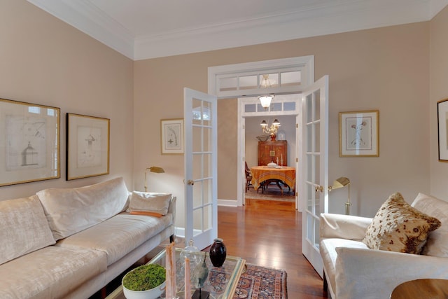 living room with hardwood / wood-style flooring, crown molding, a notable chandelier, and french doors