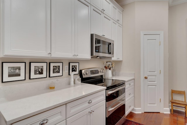 kitchen featuring ornamental molding, light hardwood / wood-style floors, white cabinets, and appliances with stainless steel finishes