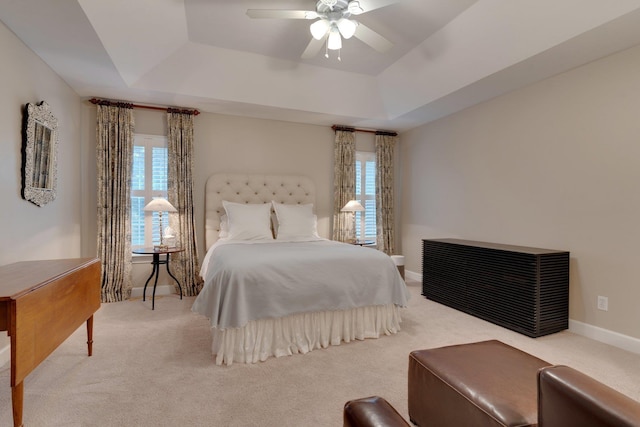 bedroom featuring light carpet, a tray ceiling, and ceiling fan