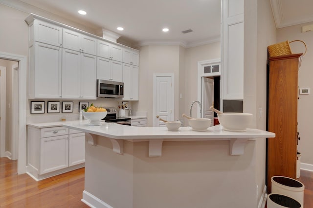 kitchen with a kitchen bar, white cabinets, and appliances with stainless steel finishes