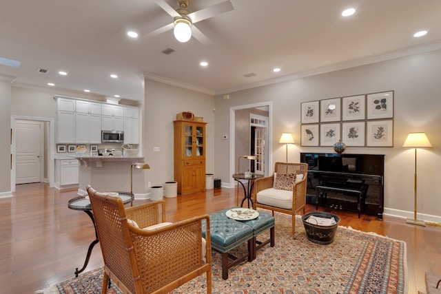 living room featuring crown molding, ceiling fan, and light hardwood / wood-style flooring