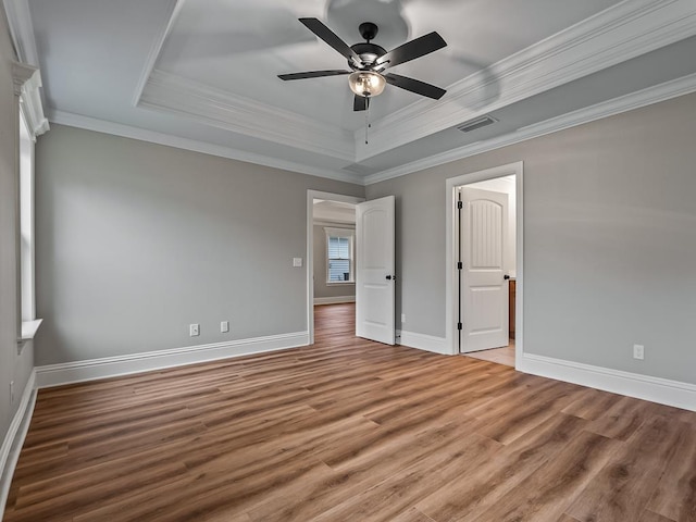 unfurnished bedroom featuring ceiling fan, hardwood / wood-style flooring, ornamental molding, and a raised ceiling