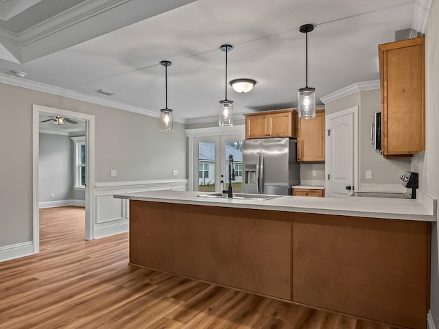 kitchen with stove, kitchen peninsula, sink, crown molding, and stainless steel fridge