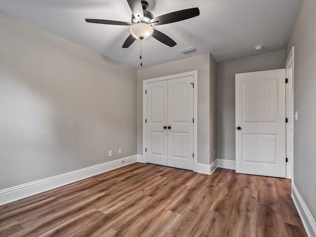 unfurnished bedroom featuring ceiling fan, wood-type flooring, and a closet