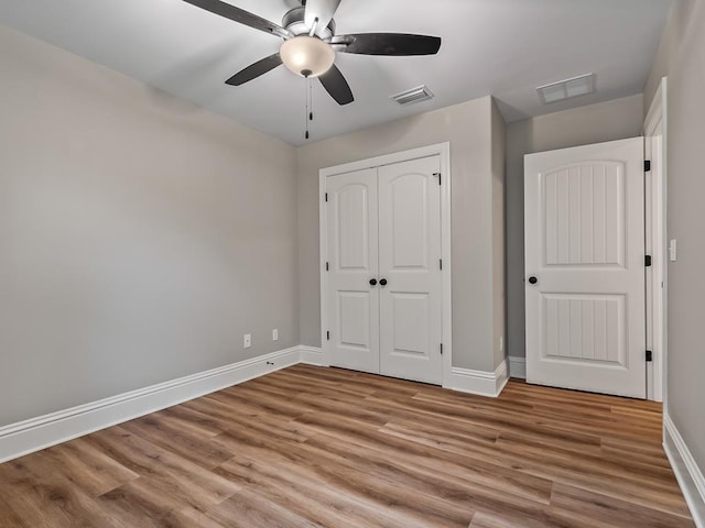 unfurnished bedroom featuring ceiling fan, a closet, and light wood-type flooring