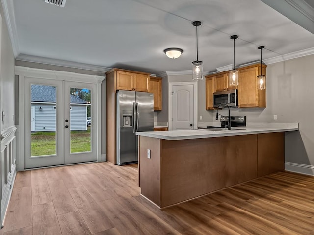 kitchen featuring kitchen peninsula, appliances with stainless steel finishes, french doors, hanging light fixtures, and ornamental molding