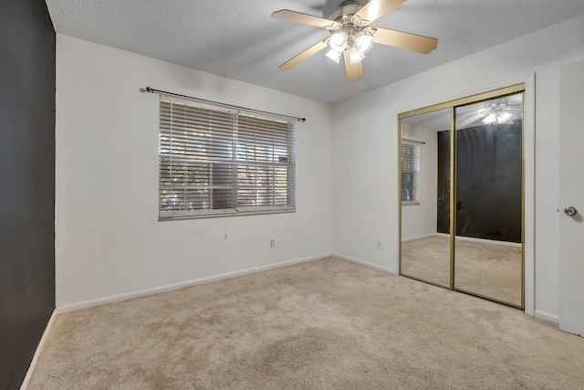 unfurnished bedroom featuring a textured ceiling, ceiling fan, light carpet, and a closet