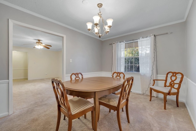 carpeted dining room featuring ceiling fan with notable chandelier and ornamental molding