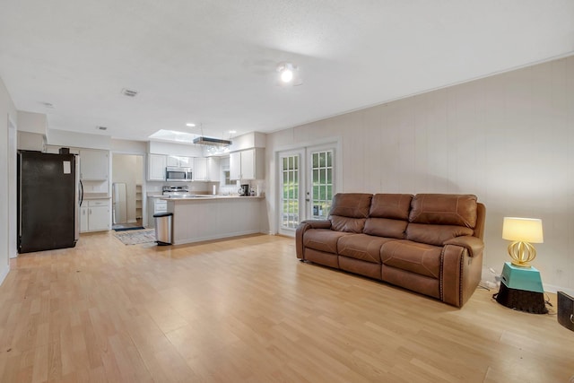 living room featuring french doors, a skylight, and light hardwood / wood-style flooring