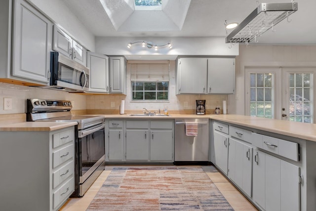 kitchen featuring gray cabinetry, decorative backsplash, light hardwood / wood-style floors, and appliances with stainless steel finishes