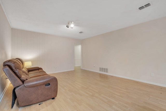 sitting room with ornamental molding and light hardwood / wood-style flooring