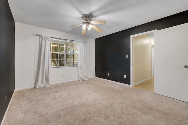 unfurnished room with ceiling fan, light colored carpet, and a textured ceiling