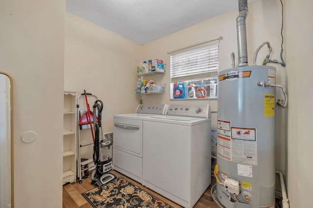 washroom featuring light wood-type flooring, washing machine and clothes dryer, a textured ceiling, and water heater