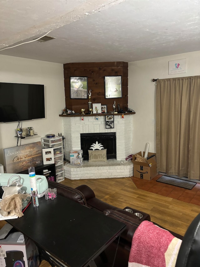 living room with a textured ceiling, a fireplace, and hardwood / wood-style flooring