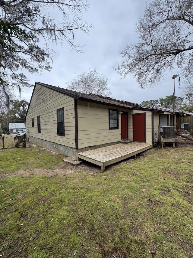 rear view of house featuring a wooden deck, a lawn, and cooling unit