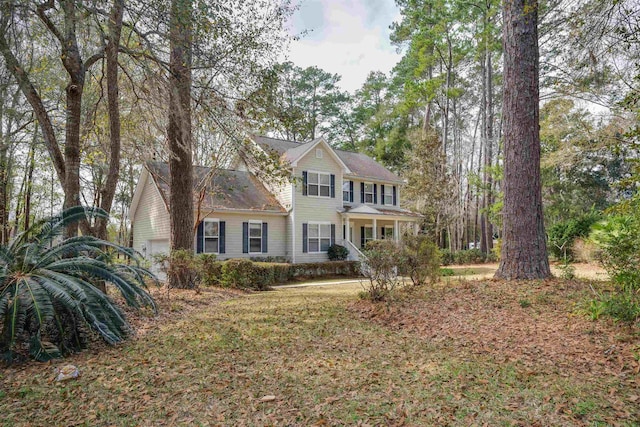 colonial inspired home featuring a garage and a front lawn