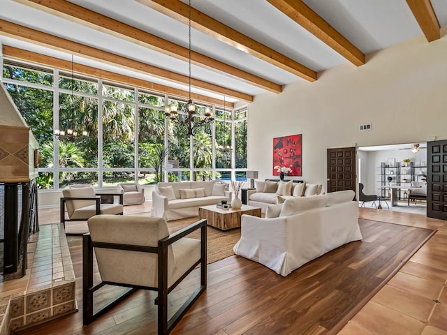 living room featuring beam ceiling, hardwood / wood-style floors, and ceiling fan with notable chandelier