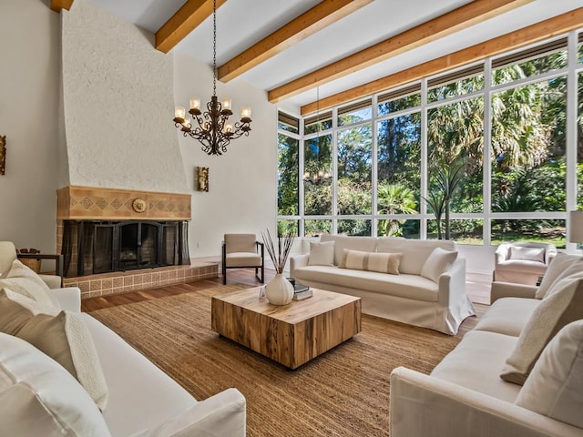 living room featuring beam ceiling, an inviting chandelier, a brick fireplace, and hardwood / wood-style floors