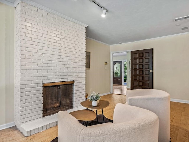 living room with a fireplace, light hardwood / wood-style floors, track lighting, and ornamental molding