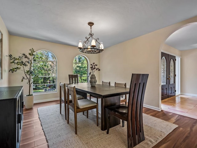 dining area with a chandelier, french doors, and wood-type flooring