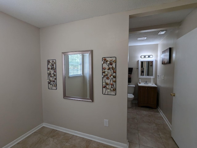 1106 Woodland Dr, Tallahassee, FL 32305 - hallway with baseboards, a textured ceiling, light tile patterned flooring, and a sink