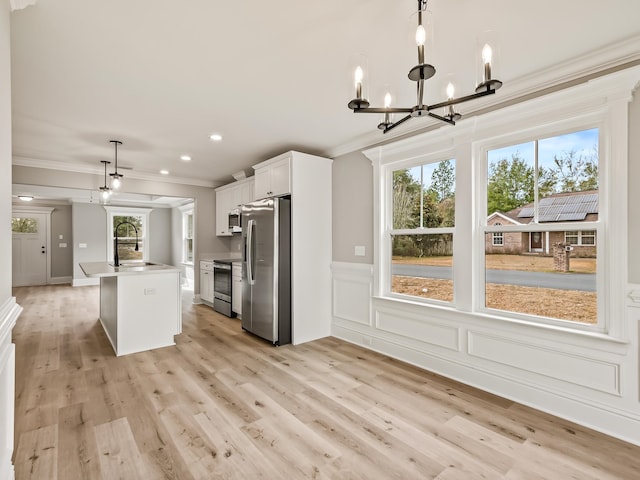 kitchen with stainless steel appliances, white cabinetry, hanging light fixtures, and plenty of natural light