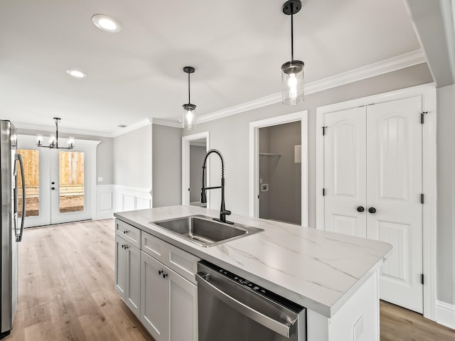 kitchen featuring decorative light fixtures, sink, stainless steel appliances, and a kitchen island with sink