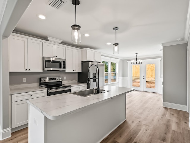 kitchen with pendant lighting, white cabinetry, an island with sink, and appliances with stainless steel finishes