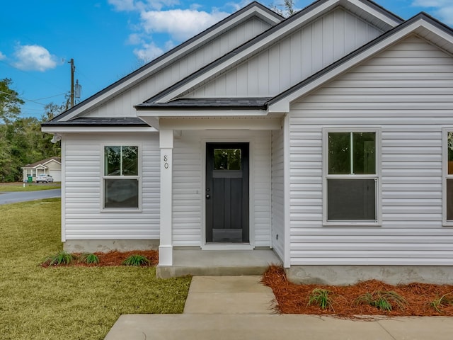 view of exterior entry featuring a lawn