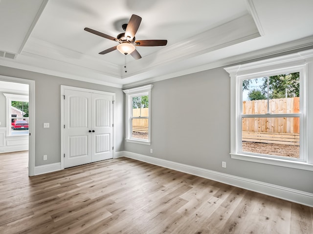 unfurnished bedroom with a tray ceiling and multiple windows