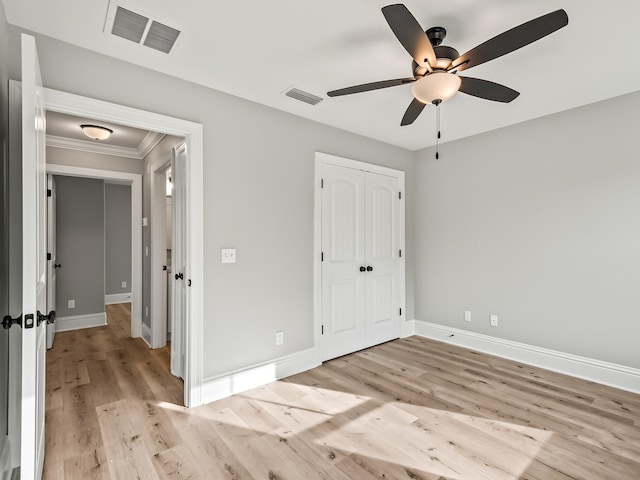 unfurnished bedroom with a closet, light hardwood / wood-style flooring, ceiling fan, and ornamental molding