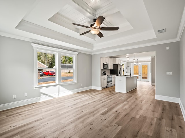 unfurnished living room featuring a tray ceiling, crown molding, light hardwood / wood-style floors, and ceiling fan with notable chandelier