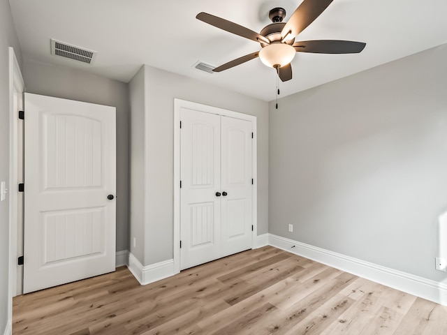 unfurnished bedroom with ceiling fan, light wood-type flooring, and a closet