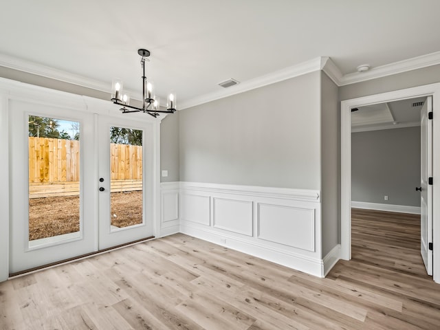 unfurnished dining area featuring french doors, light wood-type flooring, ornamental molding, and a notable chandelier