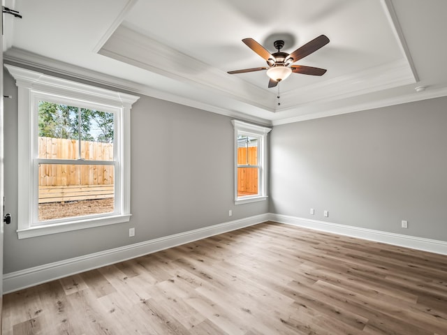 unfurnished room featuring a tray ceiling, light hardwood / wood-style flooring, ceiling fan, and crown molding