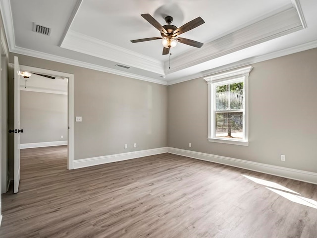 spare room with a tray ceiling, hardwood / wood-style flooring, crown molding, and ceiling fan