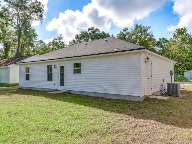 rear view of house featuring central AC unit and a yard