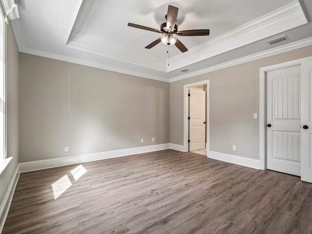 unfurnished bedroom featuring hardwood / wood-style floors, ceiling fan, crown molding, and a tray ceiling