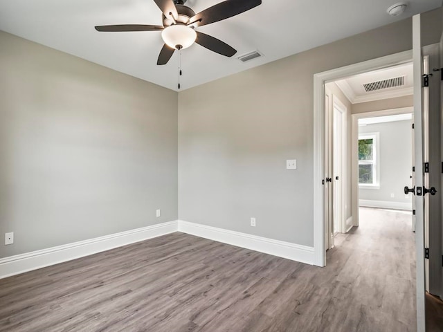 spare room featuring ceiling fan, hardwood / wood-style floors, and crown molding