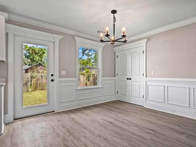 interior space with a chandelier, light hardwood / wood-style floors, a wealth of natural light, and crown molding