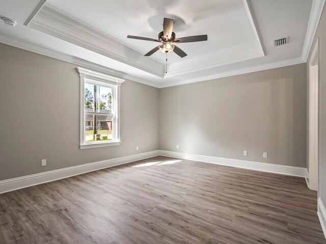 empty room featuring dark hardwood / wood-style floors, a raised ceiling, ceiling fan, and crown molding