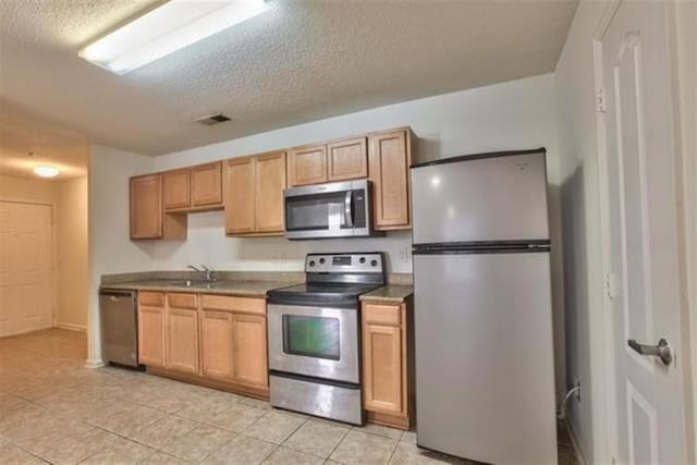 kitchen featuring sink, stainless steel appliances, a textured ceiling, and light tile patterned flooring