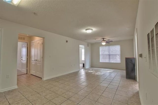 tiled spare room with ceiling fan and a textured ceiling