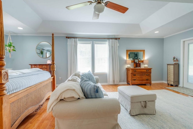 bedroom featuring ceiling fan, a raised ceiling, light hardwood / wood-style flooring, and crown molding