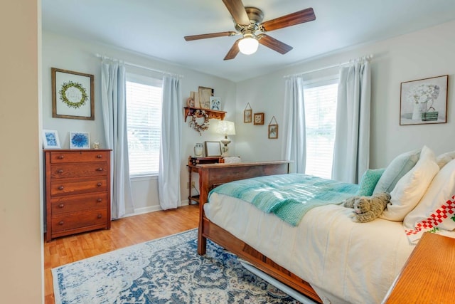 bedroom with ceiling fan, multiple windows, and light hardwood / wood-style floors