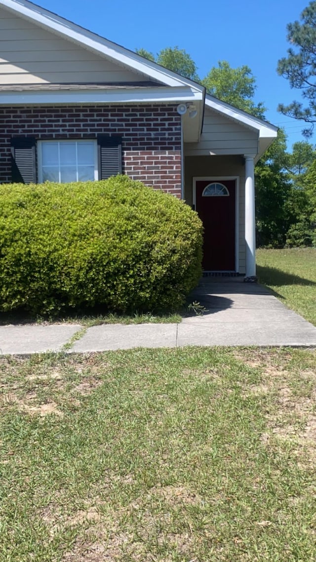 4170 Ridge Haven Rd, Tallahassee, FL 32305 - view of exterior entry featuring brick siding and a lawn